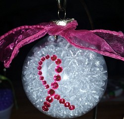 Clear glass ornament filled with tiny glass beads . Acrylic rhinestone ribbon attached to outside.