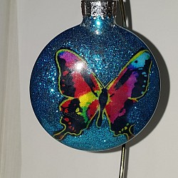 Clear glass ornament with cut out fabric butterfly and turquoise blue glitter.