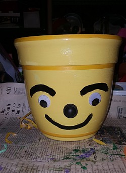 Painted whimsical plastic planter with big applied googly  eyes.