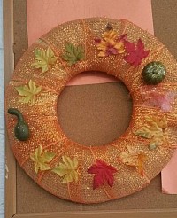 Fall wreath made from the base of a straw hat.